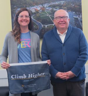 Jennifer Dietz stands to the left of Chris Gilmer, holding the "Climb Higher" banner